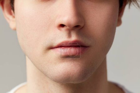 Foto de Cropped image of male face nose, lips, chin. Young model posing over grey studio background. Well-kept skin. Concept of mens health, body and skin care, hygiene and male cosmetology - Imagen libre de derechos