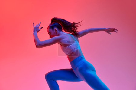 Photo for Young girl, professional runner athlete in uniform training, running over pink studio background in neon light. Concept of sportive lifestyle, health, endurance, action and motion. Ad - Royalty Free Image
