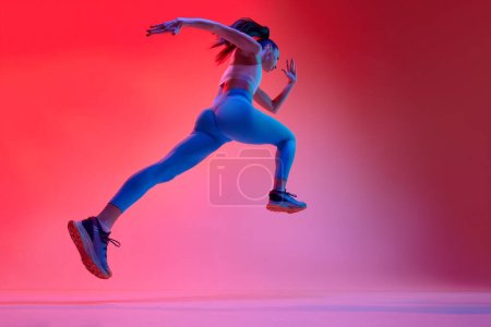 Photo for Bottom view. Young girl, professional runner athlete in uniform training, running over pink studio background in neon light. Concept of sportive lifestyle, health, endurance, action and motion. Ad - Royalty Free Image
