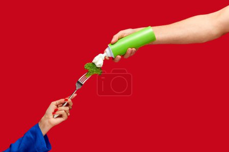 Photo for Food pop art photography. Female hand holding broccoli on fork with whipped cream against red studio background. Healthy eating. Concept of art and creativity. Complementary colors. Copy space for ad - Royalty Free Image