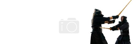 Photo for Two men, professional kendo athletes in uniform fighting, training with shinai sword against white studio background. Martial arts, sport, Japanese culture, motion concept. Banner. Copy space for ad - Royalty Free Image