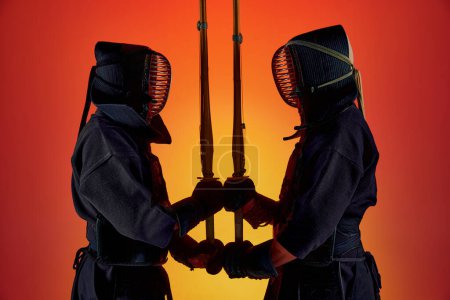 Photo for Sword to sword. Two men, professional kendo fighter, athletes in black uniform training against gradient studio background in neon light. Concept of martial arts, sport, Japanese culture, motion - Royalty Free Image