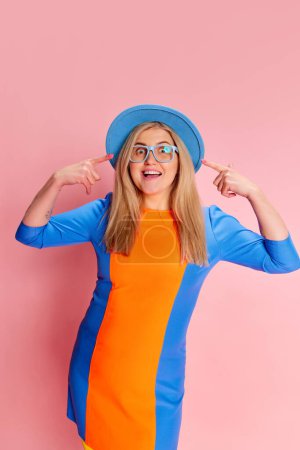 Photo for Positive emotions. Portrait of woman in colorful clothes, hat and glasses emotionally posing against pink studio background. Concept of emotions, facial expression, lifestyle and fashion - Royalty Free Image