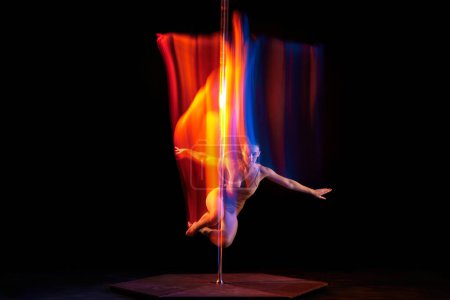 Photo for Flight. Young girl performing pole dance isolated over black studio background with mixed neon lights. Concept of sport and dance, beauty of movements, action, modern style - Royalty Free Image