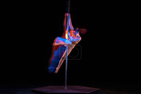 Photo for Acrobatic dance. Young girl performing pole dance isolated over black studio background with mixed neon lights. Concept of sport and dance, beauty of movements, action, modern style - Royalty Free Image