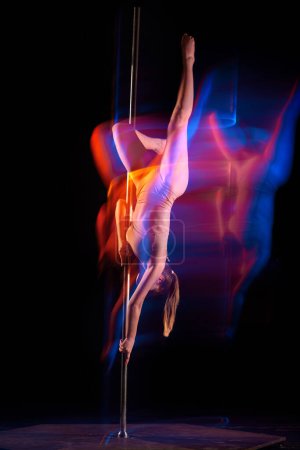 Photo for Artistic lifestyle. Young girl in bodysuit performing pole dance isolated over black studio background with mixed neon lights. Concept of sport and dance, beauty of movements, action, modern style - Royalty Free Image