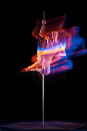 Photo for Artistic lifestyle. Young girl in bodysuit performing pole dance isolated over black studio background with mixed neon lights. Concept of sport and dance, beauty of movements, action, modern style - Royalty Free Image