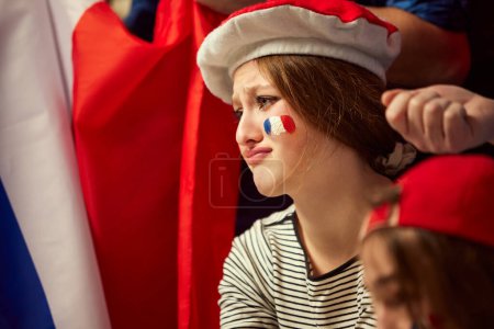 Photo for Young girl emotionally watching live football, soccer championship. Girl sitting with sad face because of losing game moment. Concept of sport, cup, world, team, event, competition - Royalty Free Image