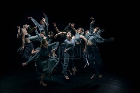 Chaotic performance. Group of young people, contemp dancers dancing against black studio background. Concept of modern freestyle dance, contemporary art, movements, hobby and creative lifestyle