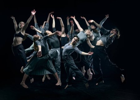 Photo for Group of young people in gray stage costumes making performance, dancing against black studio background. Concept of modern freestyle dance, contemporary art, movements, hobby and creative lifestyle - Royalty Free Image