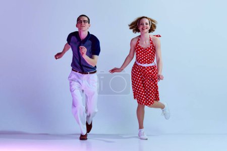 Photo for Beautiful girl and man in colorful costumes dancing retro style dances against gradient blue purple studio background. Concept of art, retro style, hobby, party, fun, movements, 60s, 70s culture - Royalty Free Image