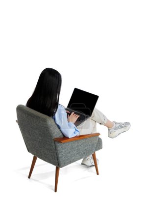 Photo for Top isometric back view. Young girl in shirt sitting on chair and working, studying in laptop isolated over white background. Concept of business, employment, education. lifestyle. Copy space for ad - Royalty Free Image