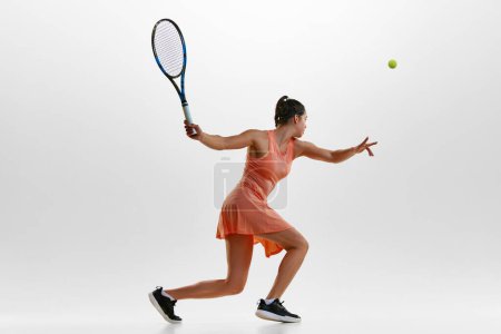 Téléchargez les photos : Balle de service avec raquette. Portrait de jeune femme, joueuse de tennis professionnelle en mouvement, formation sur fond de studio blanc. Concept de sport professionnel, mouvement, santé, action. Publicité - en image libre de droit