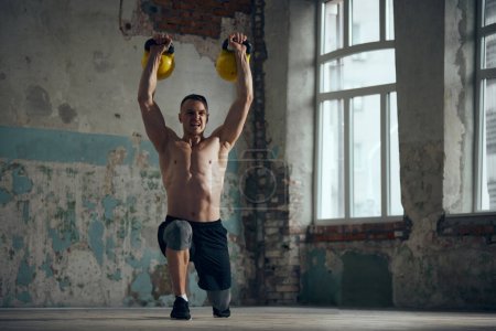 Photo for Lifting weight in motion. Young sportive man, fitness trainer with strong muscular, relief, shirtless body training indoors on daytime. Concept of sportive lifestyle, body care, fitness, hobby, health - Royalty Free Image