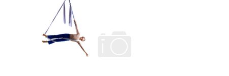 Téléchargez les photos : Image dynamique du jeune homme, gymnaste aérien professionnel, entraînement acrobatique avec tissu aérien sur fond blanc. Concept d'art, style de vie sportif, action et mouvement. Bannière. Espace de copie pour la publicité - en image libre de droit