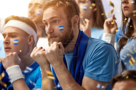 Téléchargez les photos : Hommes, fans de football regardent émotionnellement match avec des visages inquiétants, soutenir l'équipe de football de la Grèce pendant le match tendu. Concept de sport, temps libre, émotions, passe-temps et divertissement - en image libre de droit