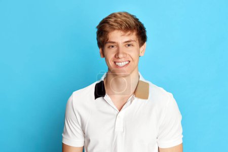 Photo for Portrait of young smiling man, student, employee in casual t-shirt posing with positive face against blue studio background. Concept of emotions, youth, facial expression, lifestyle, success - Royalty Free Image