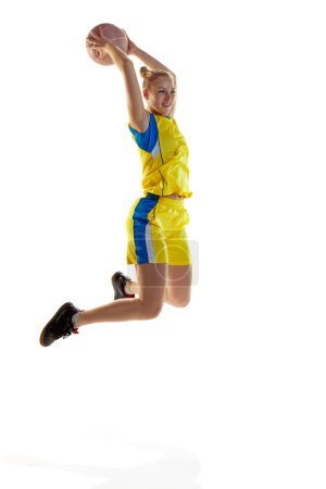 Photo for Motivated, concentrated young girl in motion, jumping with ball, playing basketball against white studio background. Concept of professional sport, hobby, healthy lifestyle, action and motion - Royalty Free Image