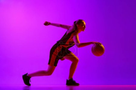 Photo for Young girl, concentrated female basketball player in motion, dribbling ball, training against white studio background. Concept of professional sport, hobby, healthy lifestyle, action and motion - Royalty Free Image