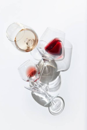 Foto de Imagen vertical de tres copas llenas de vino tinto y blanco sobre fondo blanco con luces reflejadas. Concepto de sabor, alcohol, degustación de vino, variedad, vinificación. Puesta plana - Imagen libre de derechos