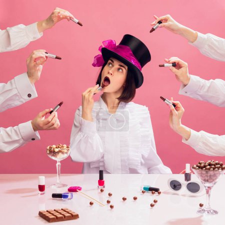 Photo for Stylish young woman in black cylinder hat and white blouse applying chocolate colour lipstick over pink background. Multi hands around. Concept of pop art, creativity, food, inspiration, party - Royalty Free Image