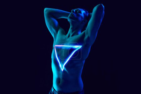 Photo for Transformation. Handsome young man with muscular body posing shirtless with neon triangle digital light reflection on body. Concept of modern photography, art, cyberpunk, techno, creativity, futurism - Royalty Free Image