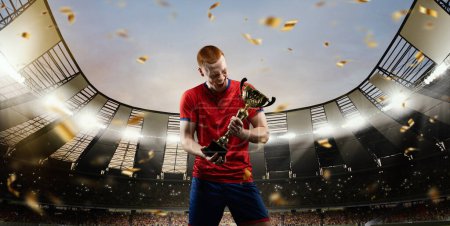 Photo for Happiness, winning championship. Proud looking young man, professional sportsman in red uniform standing on 3D sport field with cup, trophy. Concept of sport, competition, game, emotions - Royalty Free Image