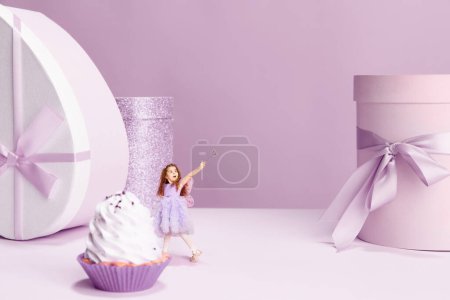 Foto de Hermosa niña en lindo vestido de pie cerca de la torta gigante y presentar cajas sobre fondo violeta. Concepto de vacaciones, celebración, regalos, saludos. ventas. Copiar espacio para anuncio - Imagen libre de derechos