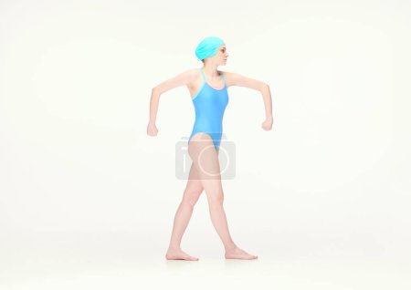 Téléchargez les photos : Jeune fille en maillot de bain bleu et bonnet de bain debout avec de larges mains isolées sur fond blanc. Concept de style rétro, sport, mode, jeunesse, vintage. Espace de copie pour la publicité - en image libre de droit