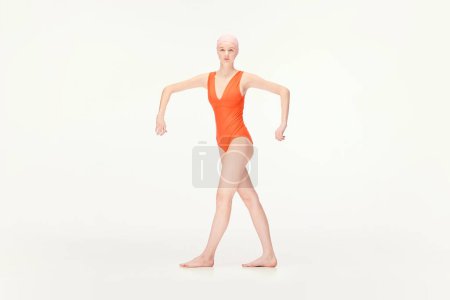 Photo for Young girl in red swimsuit and swimming cap standing in position with broad hands isolated over white background. Concept of retro style, sport, fashion, youth, vintage. Copy space for ad - Royalty Free Image