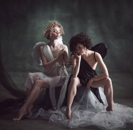 Téléchargez les photos : Portrait de deux femmes, reines, anges et démons sur fond sombre, vert, vintage. Équilibre de l'être humain. Concept d'histoire, remake, bon et mauvais, photographie créative, mode - en image libre de droit