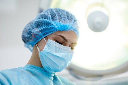Photo for Close-up image of young woman, doctor, surgeon in protective medical mask leading surgery in medical clinic, hospital in surgery room. Concept of medicine, hospital, healthcare, treatment, profession - Royalty Free Image