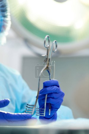 Photo for Doctors, surgeons hands holding professional medical tools. Doctor wearing protective gloves and apron. Concept of medicine, hospital, healthcare, treatment, profession - Royalty Free Image