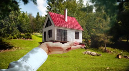 Photo for Countryside living. Female hand holding 3D model of small house against forest landscape at warm sunny day. Concept of real estate, buying house, mortgage, ownership, business, property - Royalty Free Image