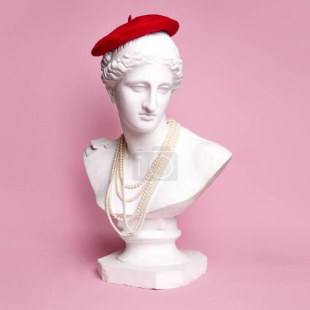 Téléchargez les photos : Buste de statue antique de jolie femme portant béret rouge et collier de perles sur fond rose. Un look parisien. Concept de créativité, modernité et vintage, art antique. Inspiration et imagination - en image libre de droit