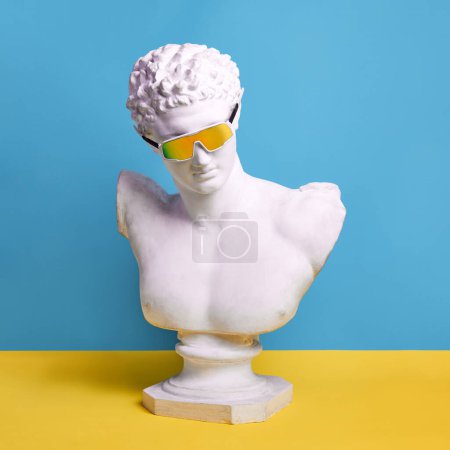 Photo for Antique male statue bust wearing stylish, trendy sunglasses against blue yellow background. Summer vibes. Concept of creativity, modernity and vintage, antique art. Inspiration and imagination - Royalty Free Image