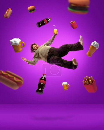 Foto de Comida rápida. collage de arte contemporáneo con hombre adulto con sobrepeso levitando entre comida chatarra, cerveza, cola, papa francesa, sándwich, hot dog sobre fondo violeta. Concepto de obesidad, malos hábitos, adiposidad - Imagen libre de derechos