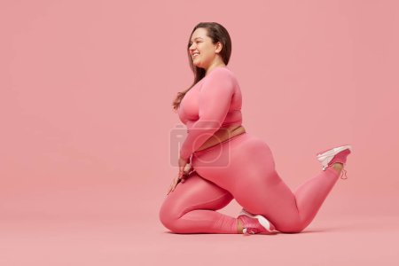 Photo for Positive, young, motivated woman with overweight body training in sportswear against pink studio background. Exercising. Concept of sport, body-positivity, weight loss, body and health care - Royalty Free Image