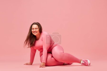 Photo for Self-care and well being. Young overweight woman training in sportswear against pink studio background. Happiness. Concept of sport, body-positivity, weight loss, body and health care - Royalty Free Image