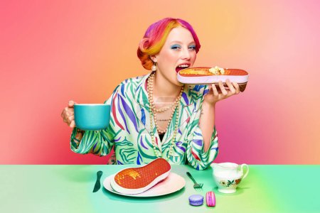 Foto de Chica bastante joven con el pelo colorido comer zapatillas surrealistas gofres con miel y mantequilla, beber café sobre fondo rosa degradado. Arte pop de comida. Concepto de estilo retro, creatividad, comida - Imagen libre de derechos