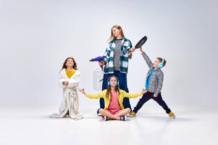 Photo for Domestic lifestyle. Portrait of young woman, other and little kids, children posing in home wear against grey studio background. Concept of family, motherhood, childhood, fashion, lifestyle - Royalty Free Image