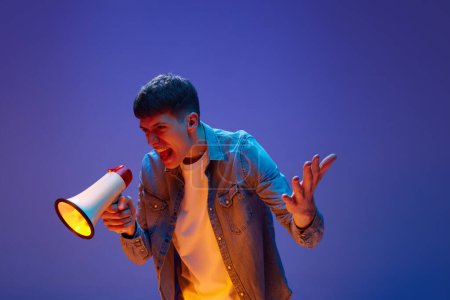 Photo for Portrait of young man, student emotionally shouting in megaphone with anger and irritation against gradient purple background in neon light. Concept of human emotions, lifestyle, youth, social issues - Royalty Free Image