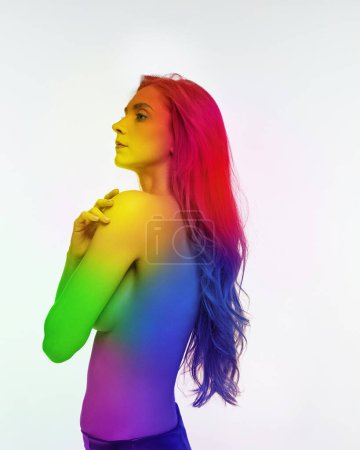 Photo for Portrait of young girl woman posing shirtless with body colored in rainbow colors against white background. Acceptance. Concept of lgbt community, support, love, human rights, pride month - Royalty Free Image