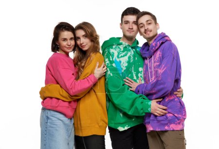 Foto de Retrato de cuatro jóvenes, amigos, parejas en sudaderas con capucha de colores posando sobre fondo blanco. Partidarios LGBTQIA. Concepto de comunidad lgbt, apoyo, amor, derechos humanos, mes del orgullo - Imagen libre de derechos