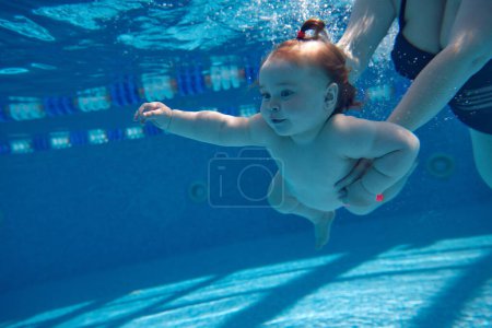 Photo for Cute, beautiful, little baby girl, toddler swimming underwater in swimming pool with mother holding her. Water sports activity. Sport, healthy and active lifestyle, childhood, fun and training concept - Royalty Free Image