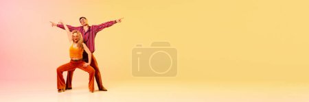 Téléchargez les photos : Émotionnel, bel homme et femme en vêtements vintage dansant danse rétro sur fond rose jaune dégradé. Concept de passe-temps, danse, mode, art, passe-temps, musique, années 70. Bannière. Espace de copie pour la publicité - en image libre de droit