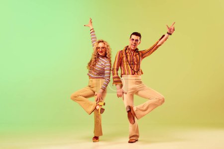Photo for Expressive, talented young couple, man and woman in stylish vintage costumes dancing against gradient green yellow background. Concept of retro style, disco dance, fashion, art, hobby, music, 70s - Royalty Free Image