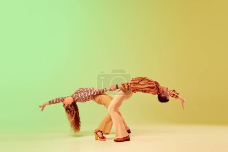 Photo for Emotional expressive young man and pretty woman in vintage style outfits dancing retro dance against gradient green yellow background. Concept of retro style, dance, fashion, art, hobby, music, 70s - Royalty Free Image