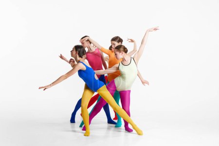 Téléchargez les photos : Groupe de jeunes filles, ballerines en vêtements multicolores faisant la performance, la danse sur fond de studio gris. Concept de beauté, créativité, style de danse classique, élégance, art contemporain - en image libre de droit