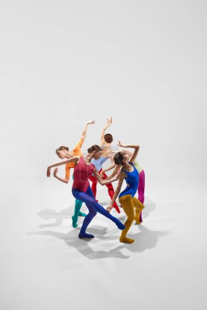 Foto de Bailarinas de ballet femeninas expresivas y artísticas en ropas brillantes y multicolores, bailando sobre fondo gris. Concepto de belleza, creatividad, danza clásica, elegancia, arte contemporáneo - Imagen libre de derechos
